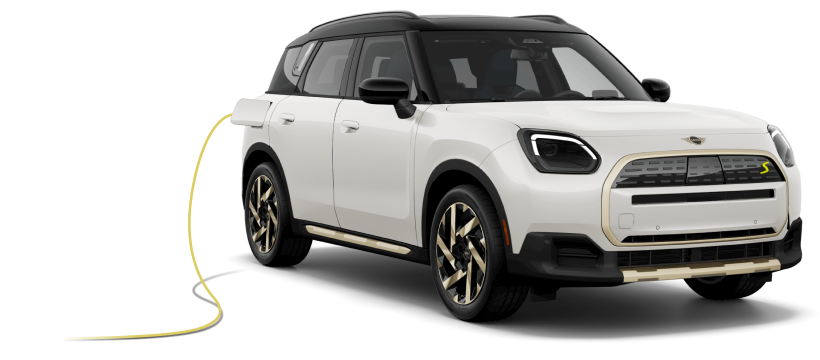 Angled view of a white MINI Countryman SE ALL4 parked with charging cord.